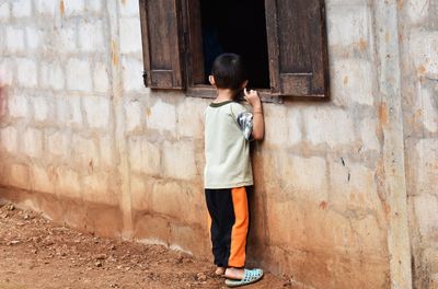 Full length of boy standing against wall