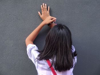 Rear view of woman with hand hair against black background