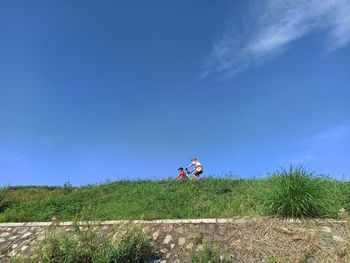Man riding motorcycle on field against blue sky