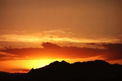 Silhouette mountains against dramatic sky during sunset