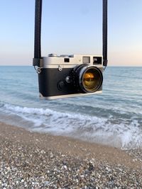 Close-up of camera on beach against sky