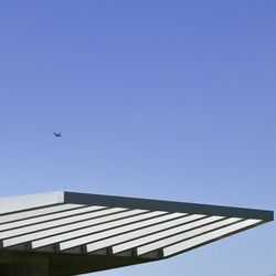 Low angle view of airplane flying against clear blue sky