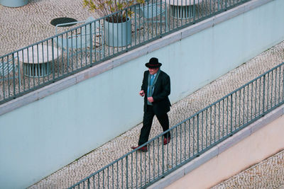 Rear view of man standing on railing against wall