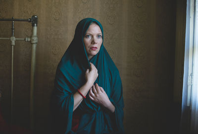 Portrait of woman standing against wall