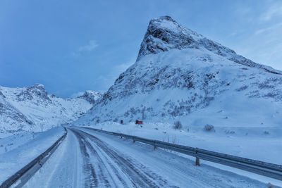 Snow covered road by mountain against sky