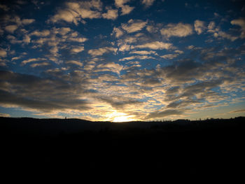 Silhouette landscape against dramatic sky during sunset