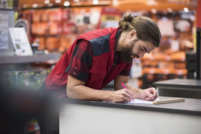 Salesman writing in book at hardware store