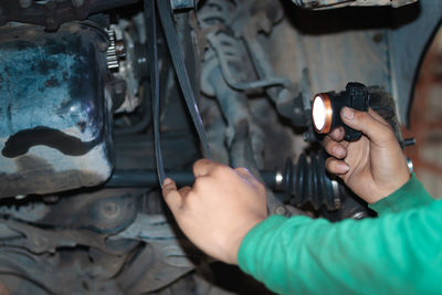 Cropped hand of mechanic repairing vehicle at garage