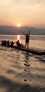 Silhouette people on beach against sky during sunset