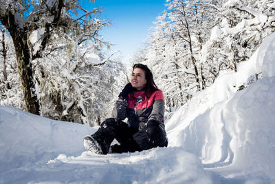 Full length of woman sitting on snow during winter