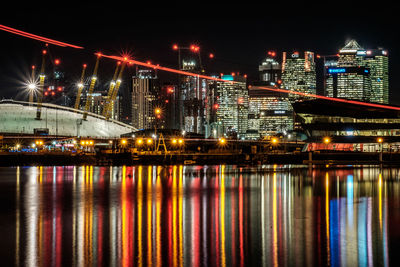 Illuminated bridge over river and buildings at night