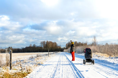 A mother with a baby carriage taking a selfie on a snowy country road in järva county