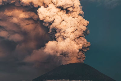 Low angle view of smoke emitting from volcanic mountain against sky