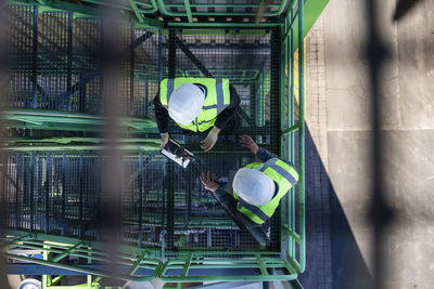 Engineers wearing hardhats discussing with tablet pc at industrial plant