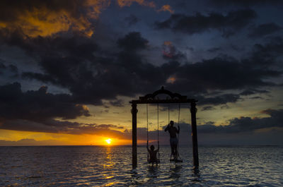 Silhouette people on beach against sky during sunset