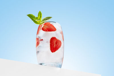 Cold and refreshing cocktail with strawberries, mint and ice cubes on blue background. summer drink.