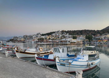 Boats moored in harbor against buildings in city