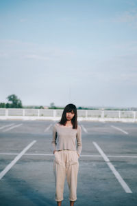 Portrait of a young woman standing on road