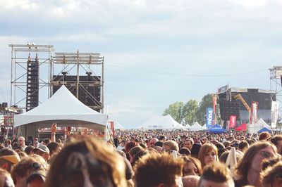 Crowd at music concert against sky in city