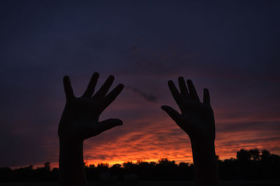 Close-up of silhouette hand against sky during sunset