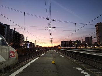 Railroad tracks in city against sky during sunset
