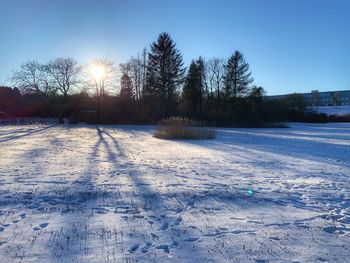 Snow covered field against sky during winter