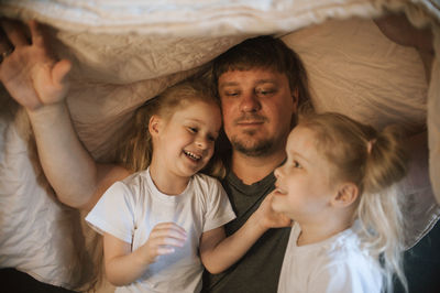Dad and daughters play in a house with a blanket
