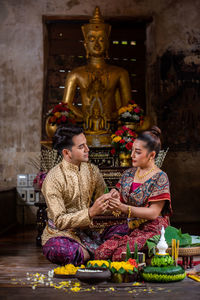 Young couple sitting against statue at temple
