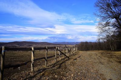 Wooden fence on field against sky