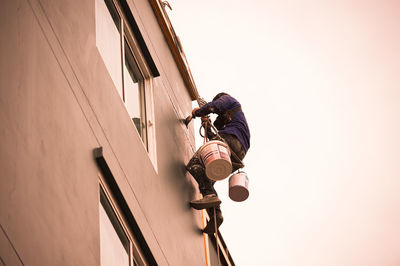Low angle view of man working against sky