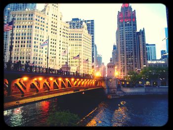 Illuminated bridge over river in city