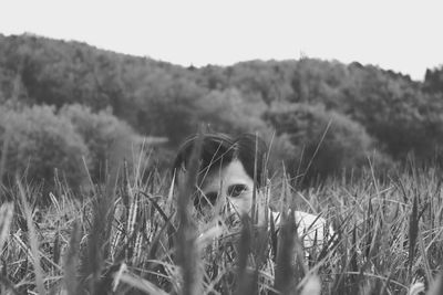 Man hiding by plants on field