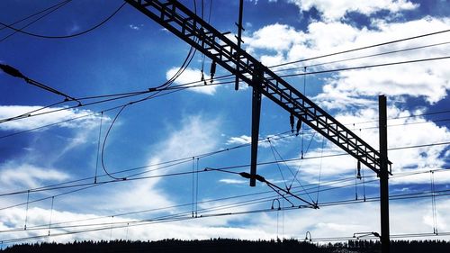 Low angle view of electricity pylon against cloudy sky