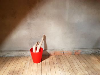 Woman sitting on floor against wall