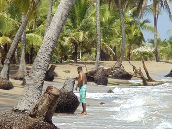 Full length of shirtless young woman standing at beach