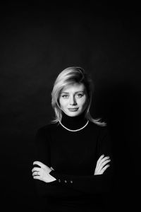 Portrait of woman with arms crossed standing against black background