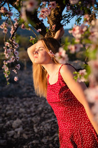 Beautiful woman standing by red flowering plant