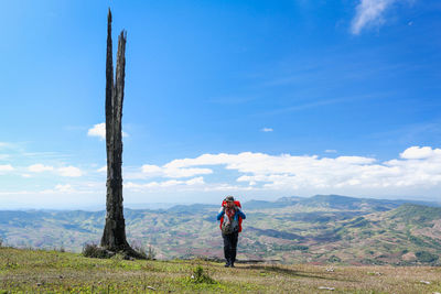 Full length of backpacker standing on mountain against sky
