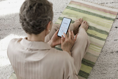 Mature woman checking data on smartphone at home