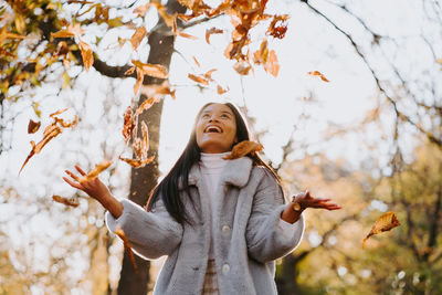 Young woman standing by tree