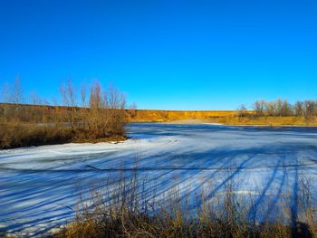 Scenic view of snow covered land against clear blue sky