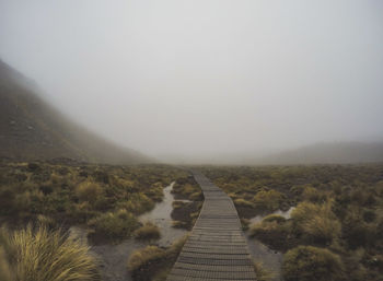 Footpath leading towards mountains against sky