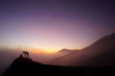 Silhouette people standing on mountain against sky during sunset