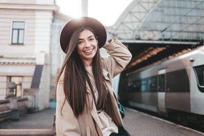 Smiling girl in hat at train station waiting for train departure