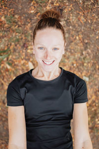 Portrait of cheerful woman in black top against flowers