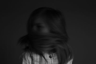 Close-up portrait of a young woman over black background