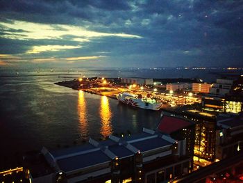 High angle view of illuminated city by sea against sky