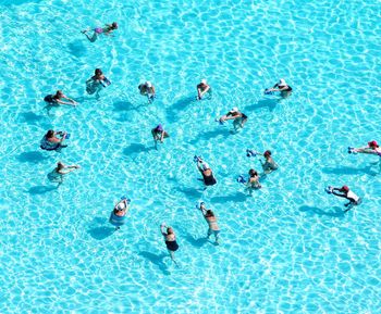 High angle view of people exercising in swimming pool during sunny day