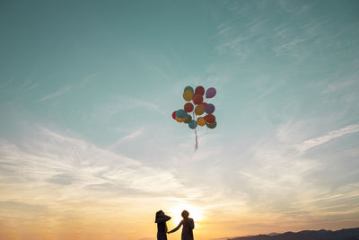 Low angle view of balloons against sky during sunset