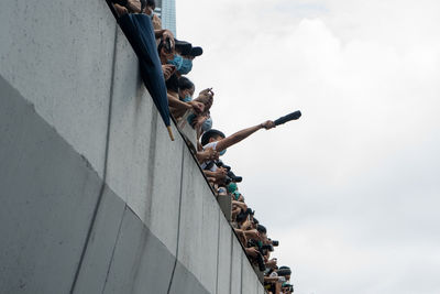 Low angle view of people on wall against sky